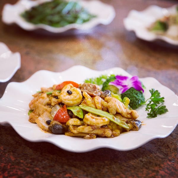 Monark Asian Bistro's stir-fried chicken and shrimp with vegetables, garnished with an orchid.